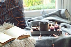 Das gemütliche Haus mit einer Tasse Tee, Decke, Buch und Kerzen genießen - so ist der Hygge Stil Foto: Von topotishka / shutterstock.com